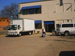Equipment truck unloads outside building.